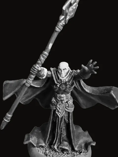 An unpainted pewter miniature of Eloryn Vale — a hooded, robed figure with arms outstretched, holding a long ornate staff crowned by a pointed crystal, heavy flowing robes curled at the hem, standing on a round base